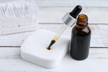 Bottle of iodine with dropper, cotton pads and swabs on white wooden table, closeup