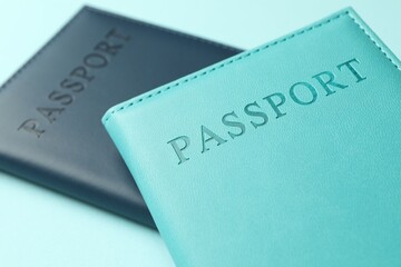 Passports in color covers on light blue background, closeup