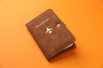 Passport in leather cover on orange background, closeup