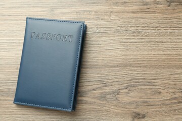 Passport in dark blue cover on wooden table, top view. Space for text