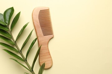 Wooden comb and branch with leaves on beige background, flat lay. Space for text