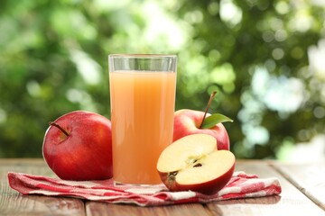 Tasty apple juice and fresh fruits on wooden table against blurred background