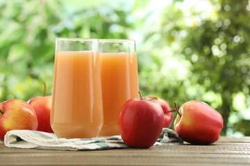 Tasty apple juice and fresh fruits on wooden table against blurred background