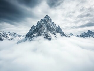 Majestic mountain peak emerging from clouds under a dramatic sky.