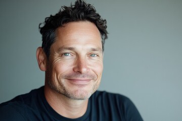 Obraz premium Capturing the essence of joy in a candid moment of a smiling man with curly hair against a simple backdrop