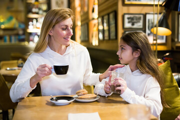 Mom and daughter drink morning coffee in a cafe