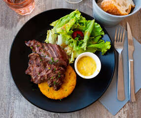 Onglet de bouef - traditional French meat dish with spices, lettuce, vegetables and cheese sauce