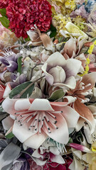 A stunning arrangement of artificial flowers featuring elegant magnolias in soft blush tones, vibrant red blossoms, and delicate pastel accents. A perfect display for weddings, home decor, or festive 