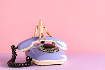 Lilac retro telephone with human figurine on color background