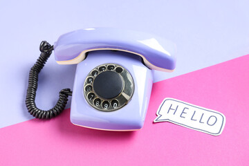 Lilac retro telephone and speech bubble with text HELLO on color background
