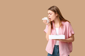 Young woman with tissue box suffering from allergy on brown background