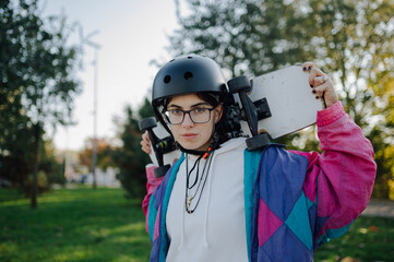 Young skater woman holding skateboard in a park wearing protective helmet © Zamrznuti tonovi