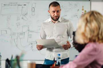 Professor holding documents explaining lesson to university students in classroom