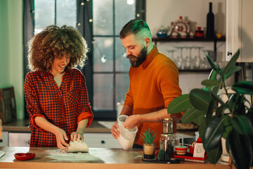Happy couple kneading dough and baking together in kitchen