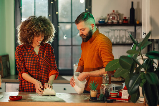 Happy couple kneading dough and baking together in kitchen