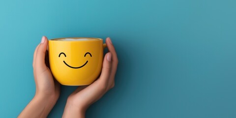 A playful close-up of hands gently holding a yellow coffee mug with a frothy smiley face