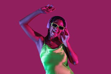Young  African-American woman listening to music on color background