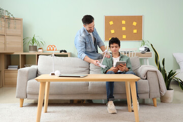 Father with wind turbine model and his son using tablet computer at home