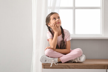 Thoughtful little girl sitting on commode at home