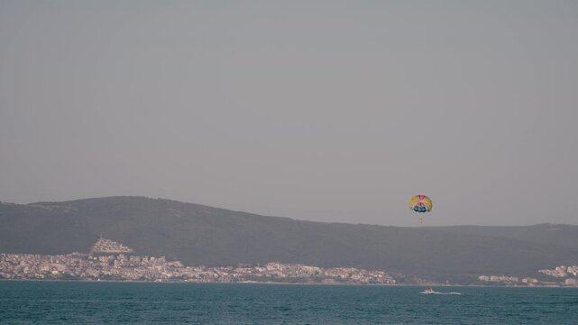 Double parasail over stunning coastline, admiring bright blue sea and distant city under clear sky. Soar through air and create unforgettable memories in this beautiful setting