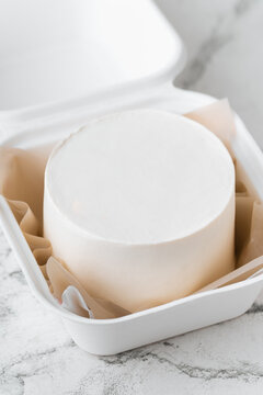 Clean white little bento cake without decoration in a gift box with brown paper inside. Cake mockup with a free space for your own decoration on the white marble background
