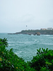 Biarritz coastline with a lighthouse blue sea and overcast rainy weather