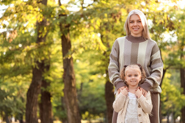 Little girl with her mother hugging in park on autumn day