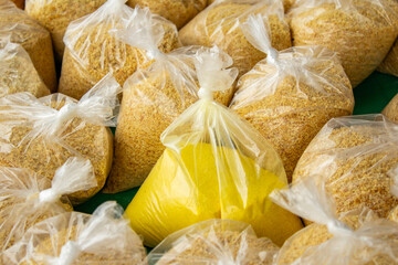 Detalhe em close up de alguns saquinhos plásticos com farinha de mandioca sobre uma mesa, expostos para venda em um comércio local.
