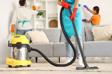 Female janitor vacuum cleaning carpet in room