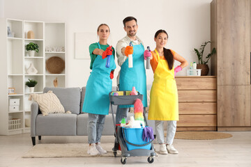 Team of janitors with cleaning supplies in room