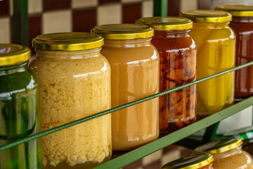 Alguns vidros com doces em compotas organizados em uma prateleira, em exposição para venda.