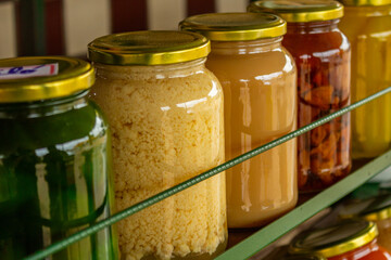 Close up em alguns vidros com doces em compotas organizados em uma prateleira, em exposição para venda.