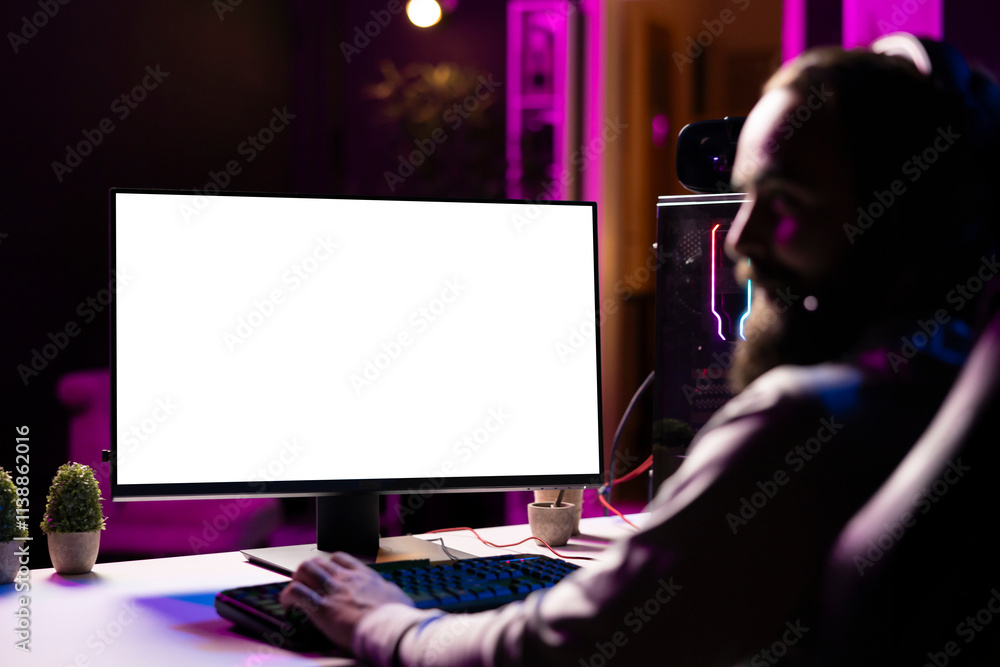 Poster man in dimly lit apartment playing video games on isolated screen gaming pc at computer desk, enjoyi