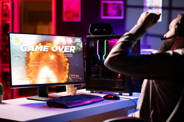 Upset gamer at desk frustrated after receiving game over screen, getting his spaceship destroyed in...