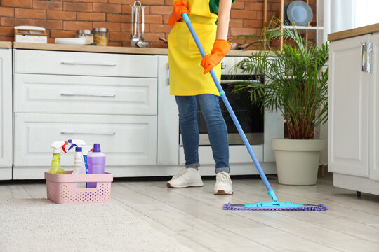 Young woman with cleaning supplies mopping floor at home