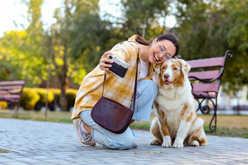 Young woman with Australian Shepherd dog taking selfie in park