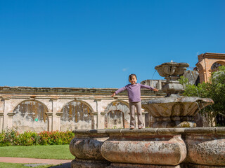 Latina girl poses for a photo on a beautiful colonial fountain.