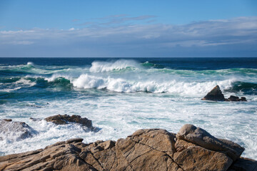 Scenic view of Pacific Ocean waves at the coast seen from Spanish Bay Vista Point, Del Monte Forest, California, USA against blue sky with clouds