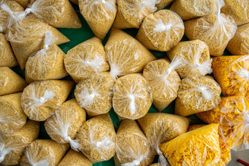 Vários saquinhos plásticos com farinha de mandioca expostos para venda em um comércio local. Fotografados de cima.