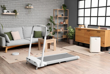 Interior of living room with sofa, treadmill and appliances