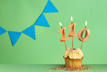 Birthday card with number 110 candle - Cupcake on a green background with blue pennants.