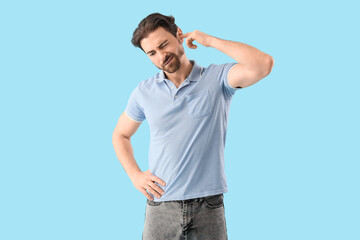Young man suffering from ear pain on blue background