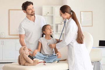 Female pediatrician with stethoscope listening to girl and father in clinic