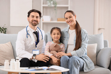 Obraz premium Male pediatrician with girl and mother sitting on sofa at home
