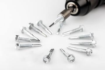 Screwdriver with a screw attachment. Self-tapping screws for metal on a white background.