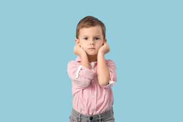 Little boy suffering from ear pain on blue background
