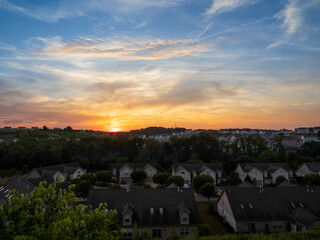 A breathtaking sunset casts a golden glow over a suburban neighborhood, creating a peaceful and serene atmosphere.