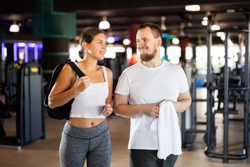 Girl and man visitors of gym chat after workout, consult about correct performance of exercises....