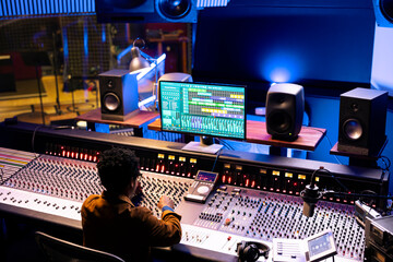 African american audio expert editing tunes with digital software on pc, mixing and mastering...