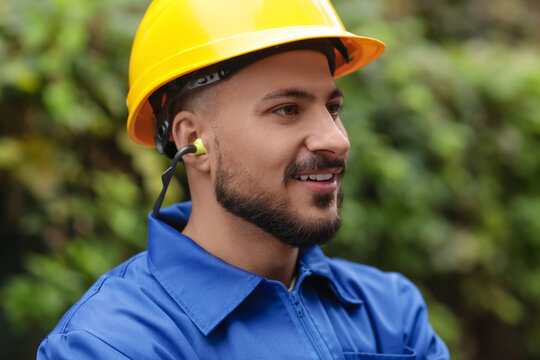 Male builder in hardhat with earplugs outdoors, closeup
